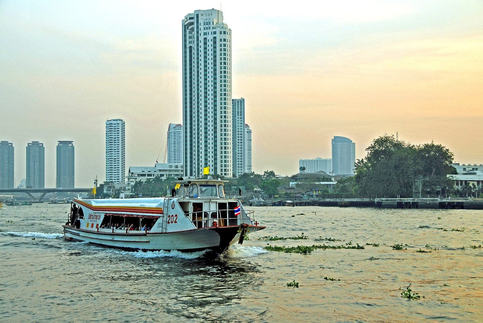 Chao Phraya Express Boat passing high-rise buildings on the river in Bangkok
