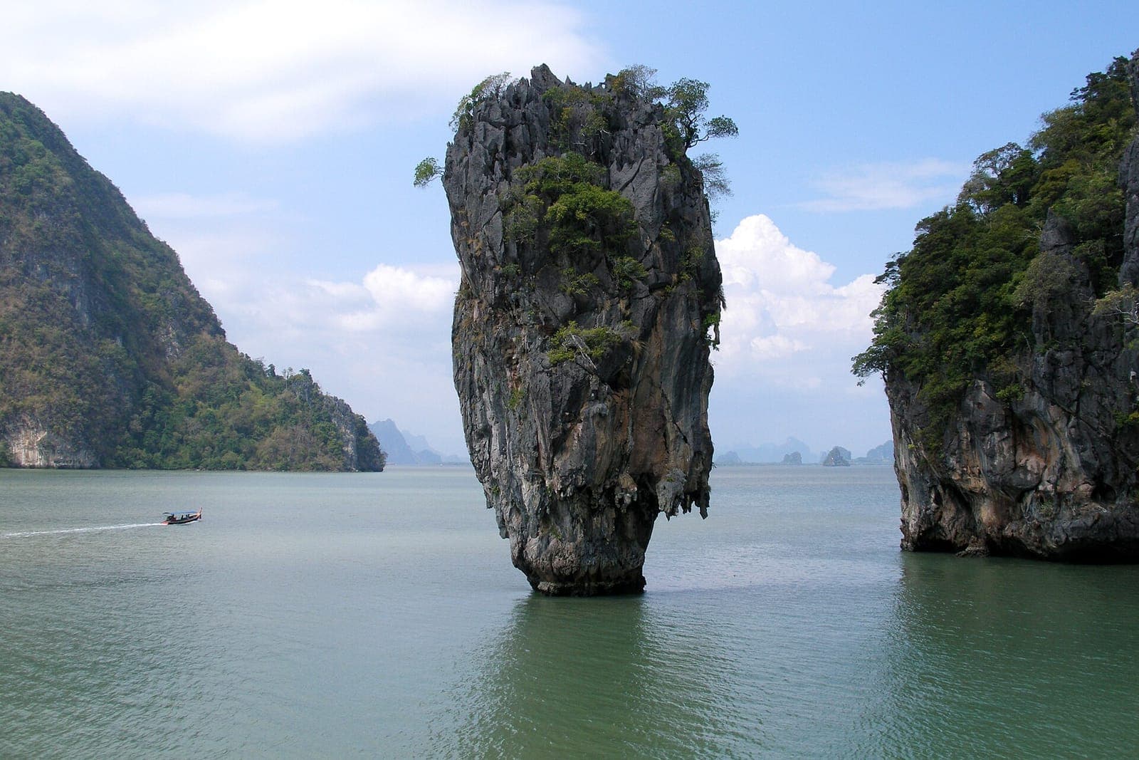 Ko Tapu limestone pinnacle, known as James Bond Island, rising from the water of Phang Nga Bay with a small boat passing